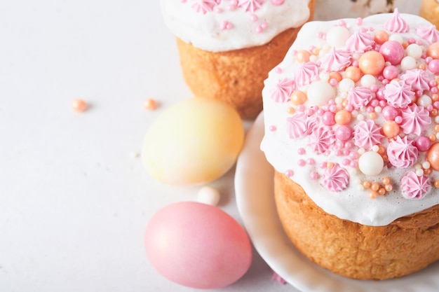 Traditional Easter sweet bread or cakes with white icing and sugar decor colored eggs and cherry blossom tree branch over white table Various Spring Easter cakes Happy Easter day Selective focus