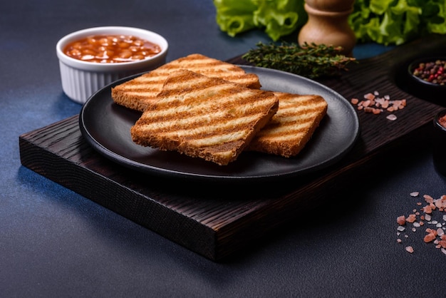 Traditional English breakfast with eggs toast sausages beans spices and herbs on a grey ceramic plate