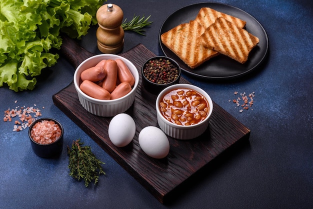 Traditional English breakfast with eggs toast sausages beans spices and herbs on a grey ceramic plate