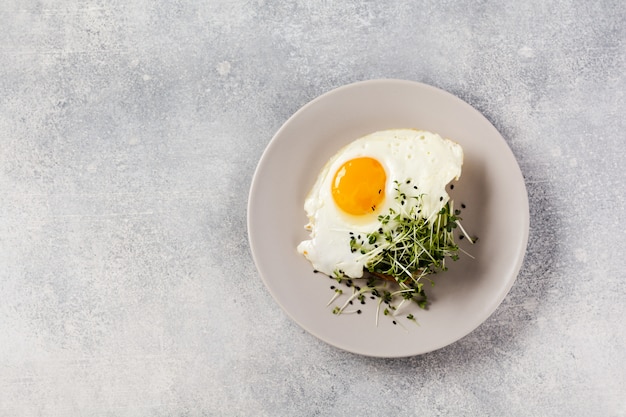 Traditional English breakfast with fried eggs in ceramic plate on gray concrete background