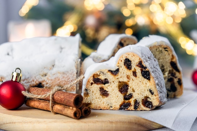 Traditional festive European pastry with raisins nuts dried fruit and marzipan Christmas stollen pie with cinnamon red ball and Christmas lights Recipe of homemade dessert for holiday season