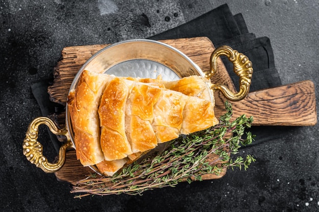 Traditional feta cheese phyllo pastry pie in rustic skillet Black background Top view