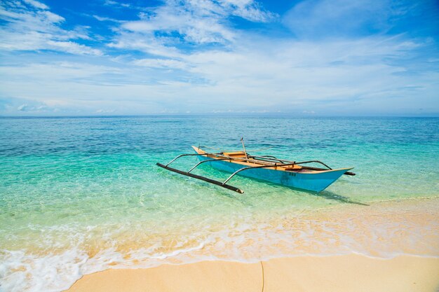 Traditional Filipino boat on a white beach in the sea