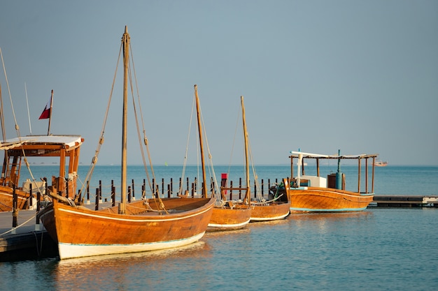 Traditional fishing boat At docked at long berth with calm blue water.