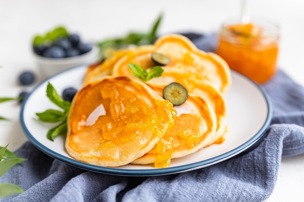 Traditional fluffy pancakes with orange jam blueberries coconut chips and mint for healthy breakfast