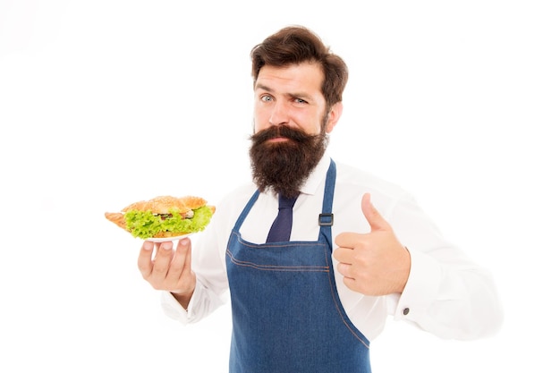 Traditional french croissant. Man bearded waiter wear apron carry plate with dish. Delicious croissant. Cafe concept. Guy serving croissant stuffed with lettuce and fresh vegetables. Healthy food.