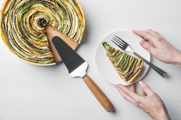 Traditional french ratatouille vegetable pie on a white wooden background with cut out slice