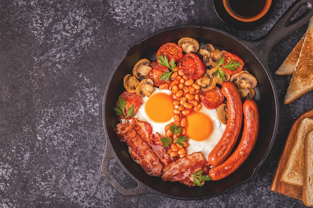 Traditional full English breakfast with fried eggs, sausages, beans, mushrooms, grilled tomatoes and bacon