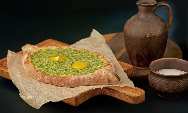 Traditional georgian pastry adjarian khachapuri with cheese and raw yolk Khachapuri with egg on wooden background in rustic style Adjara khachapuri with ingredients Georgian cuisine