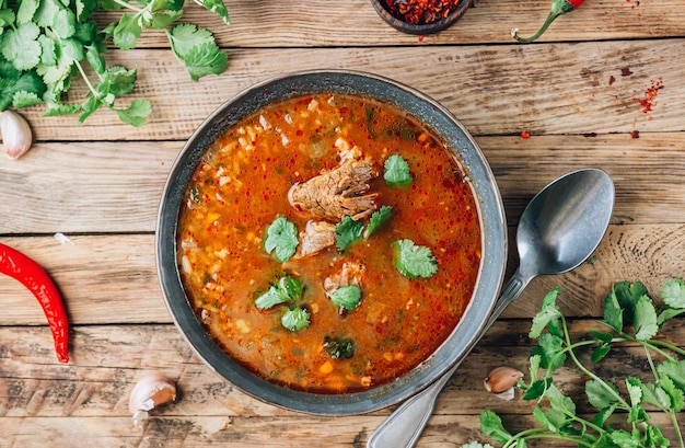 Traditional georgian tomato soup kharcho with beef and rice on rustic wooden background