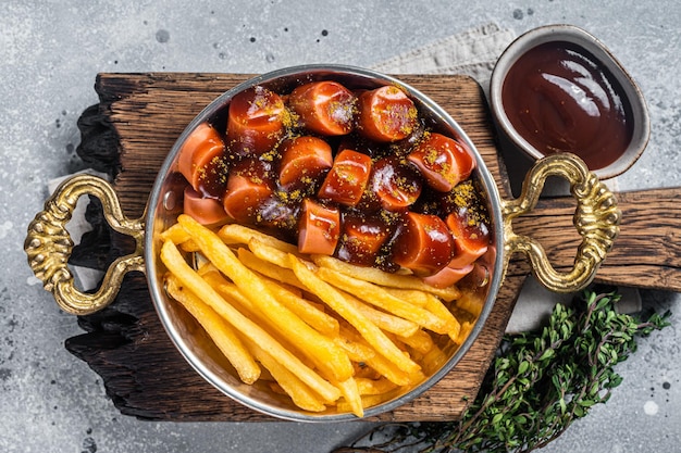 Traditional German currywurst sausage served with chips or French fries in a pan Gray background Top view