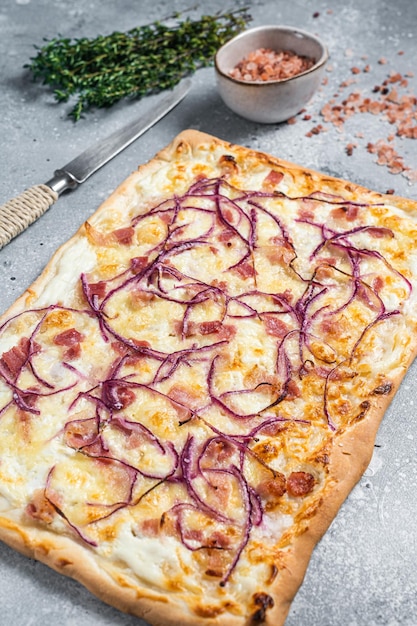 Traditional German Flammkuchen pie with ham and onion Gray background Top view