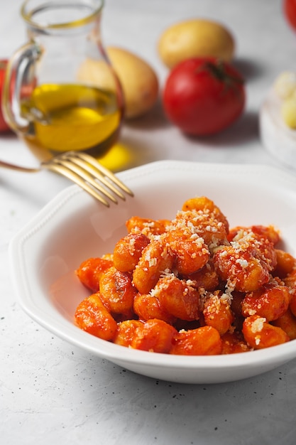 Traditional gnocchi with tomato sauce and cheese in a white plate, close up shot