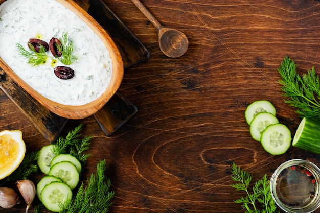 Traditional Greek sauce Tzatziki in olive wooden bowl on old rustic background