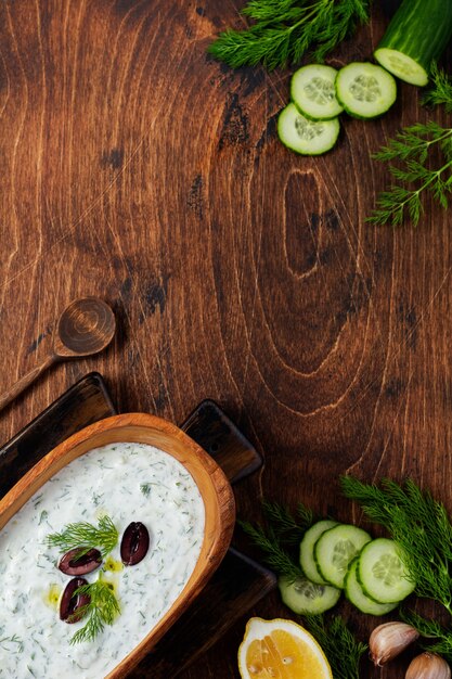 Traditional Greek sauce Tzatziki in olive wooden bowl on old rustic surface