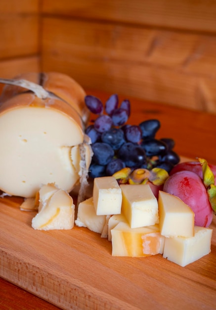 Traditional Greek smoked cheese Metsovone on a wooden board with grapes and persimmons in Greece