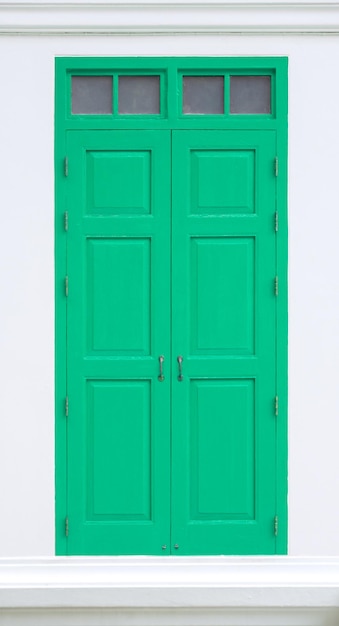 Traditional green door wooden of an old on white wallin Thailand