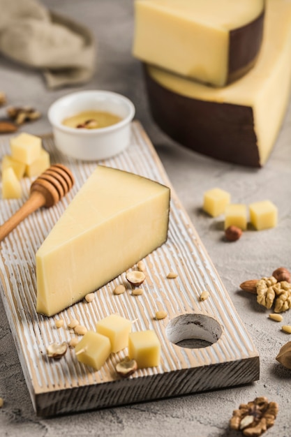 Traditional hard Parmesan cheese is cut into pieces on a light wooden board. An excellent product for cooking poultry dishes, soups, pasta. Light wooden background. Side view.