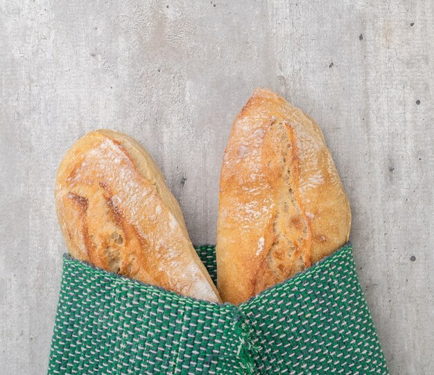 Traditional homemade french baguette breads in a green textile with copy space.