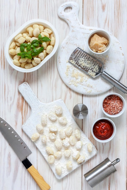 Traditional homemade raw italian potato gnocchi on white wooden background