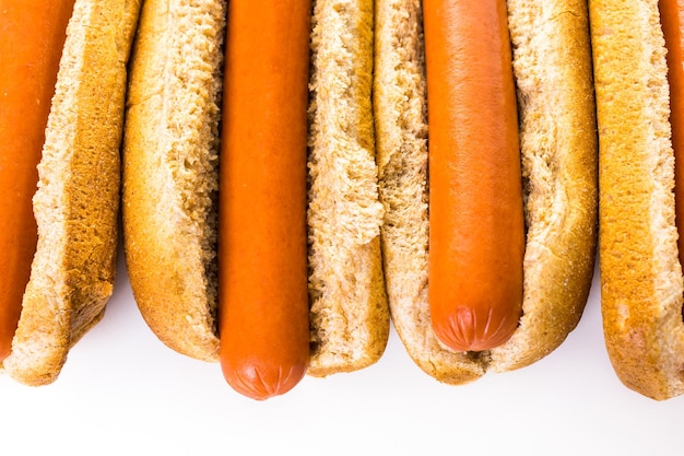 Traditional hot dogs on a white hot dog bun on a white background.