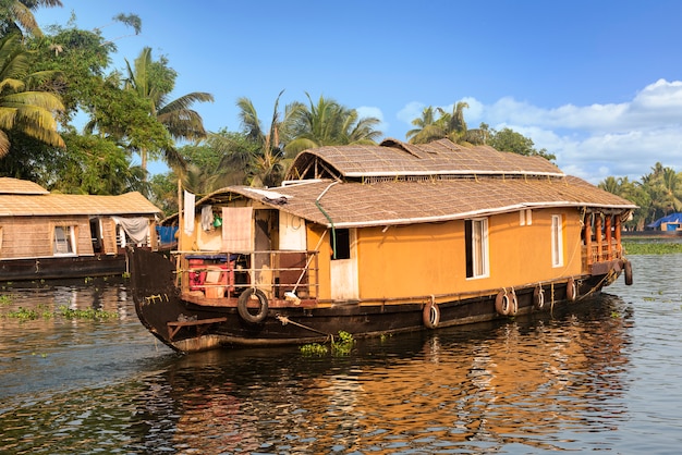 traditional house boat is anchored on the shores of a fishing lake in India.