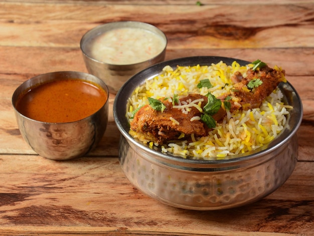 Traditional Hyderabadi Chicken dum Biryani made of Basmati rice cooked with masala spices served with Onion raita and Salan selective focus