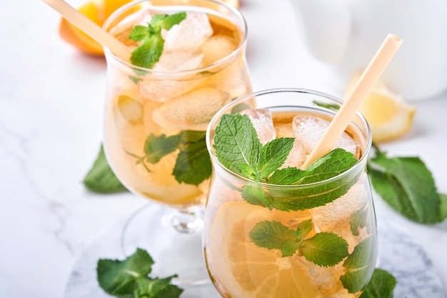 Traditional iced tea with lemon and ice in tall glasses on marble table background Iced tea with lemon. Selective focus. Refreshment cold summer drink.