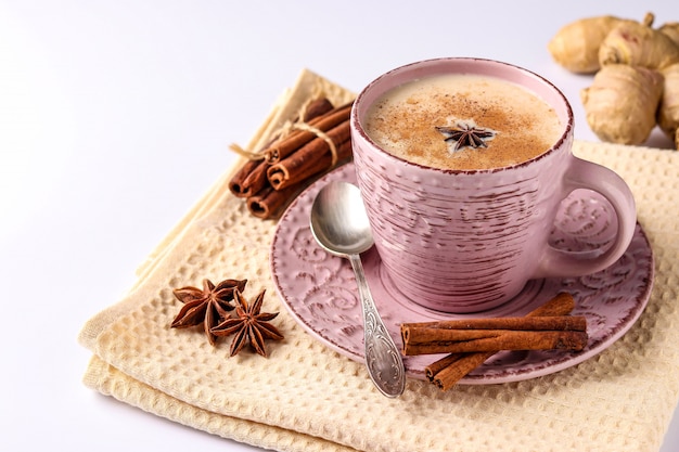 Traditional indian drink - masala tea with spices in pink cup on a white surface, horizontal orientation, copy space