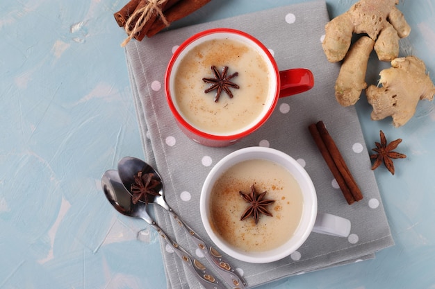 Traditional indian masala tea with spices in two cups on light blue