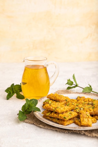 Traditional iranian dessert sohan with glass of green tea on a gray concrete background side view close up copy space