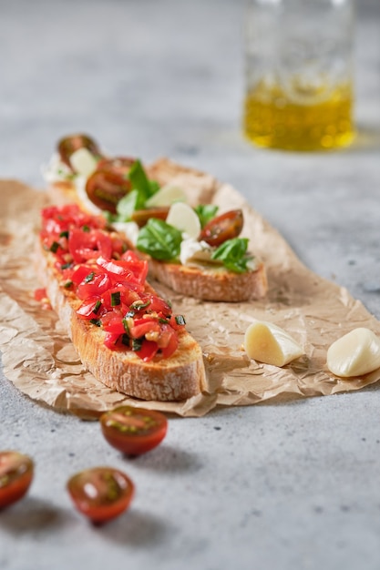 Traditional Italian bruschetta with tomato, oregano, olive oil and basil. The process of preparing snacks.