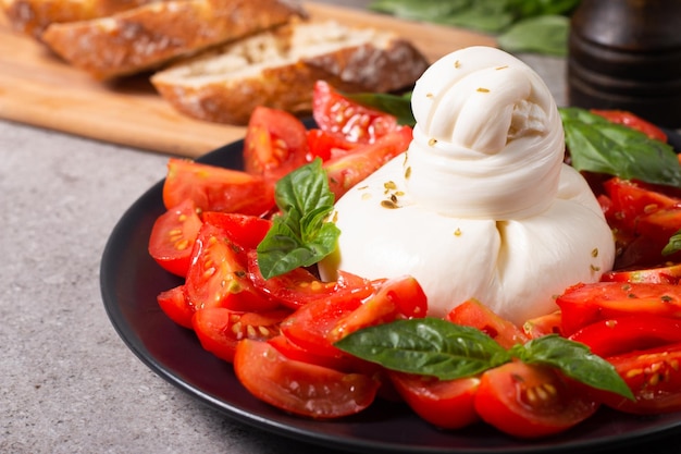 Traditional Italian burrata cheese with salad of delicious cherry tomato, basil leaves and olive oil