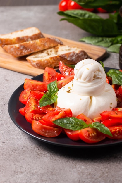 Traditional Italian burrata cheese with salad of delicious cherry tomato, basil leaves and olive oil