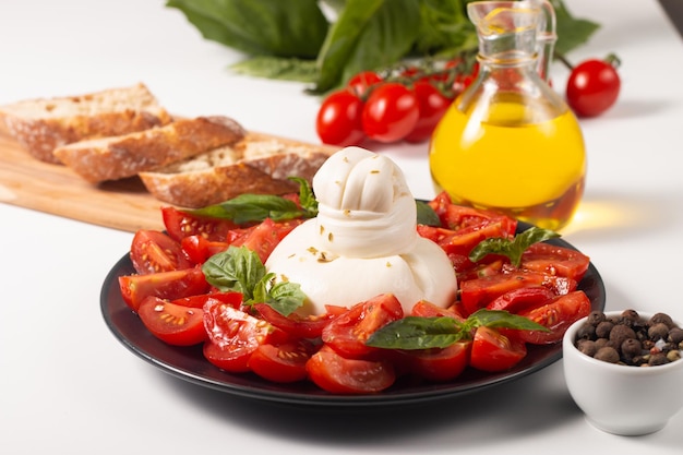 Traditional Italian burrata cheese with salad of delicious cherry tomato, basil leaves and olive oil