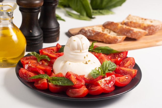 Traditional Italian burrata cheese with salad of delicious cherry tomato, basil leaves and olive oil