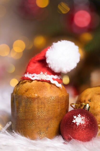 Traditional Italian cake- panettone in Santa Claus hat. Winter holidays blurred background