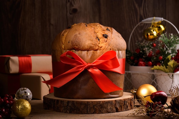 Traditional italian christmas cake panettone with red bow and festive decoration on wooden rustic