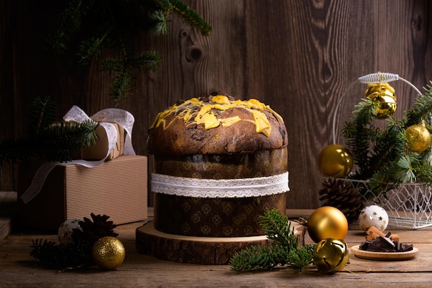 Traditional italian christmas cake panettone with white ribbon and festive decoration on wooden