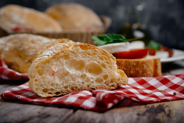 Traditional Italian ciabatta bread with herbs as closeup on checkered napkin