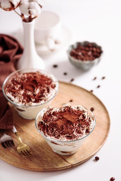 Traditional Italian dessert tiramisu in glasses on white table Soft focus