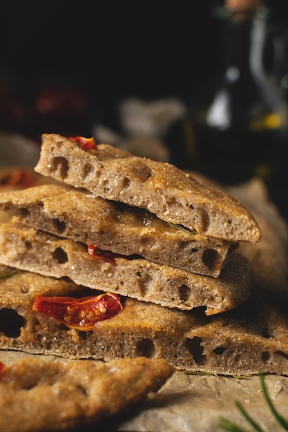 Traditional italian homemade focaccia bread with tomatoes and rosemary on rustic wooden background