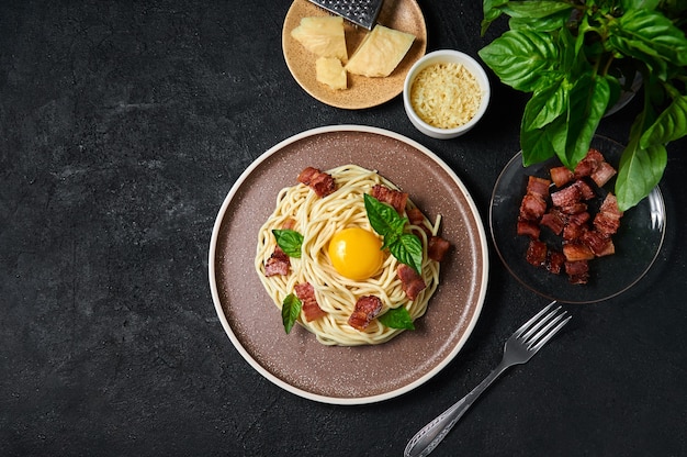 Traditional italian pasta carbonara with bacon cheese and egg yolk on plate on dark background top