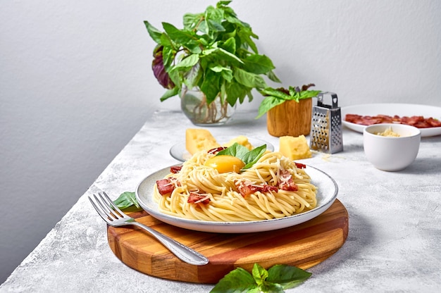 Photo traditional italian pasta carbonara with bacon, cheese and egg yolk on plate on light background.