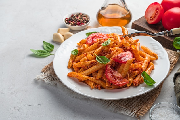 Traditional Italian pasta with tomato and meat bolognese sauce on a gray background. Side view, copy space.