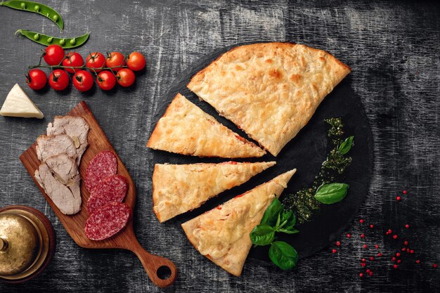 Photo traditional italian pizza calzone with ingredients on a stone and dark wooden scratched background