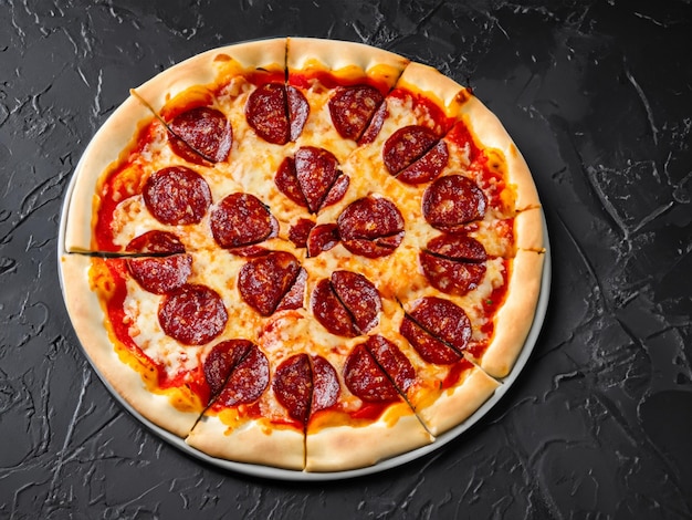 Traditional italian pizza pepperoni with salami and cheese on a dark slate stone metal or concrete