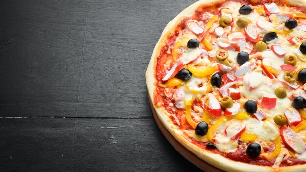 Traditional Italian pizza with crab sticks and olives Top view free space for your text Rustic style