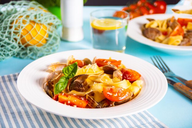 Traditional italian seafood pasta on white plate with clams vongole with tomatoes and basil Tasty and delisious food