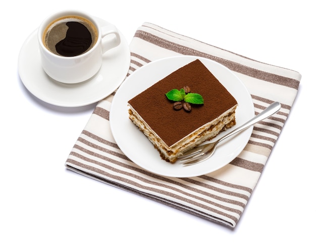 Traditional Italian Tiramisu dessert square portion on ceramic plate and cup of fresh espresso coffee isolated